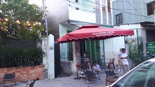 un paraguas rojo sentado fuera de un café con gente sentada en sillas en Hong CuXaThanhLich en Da Nang