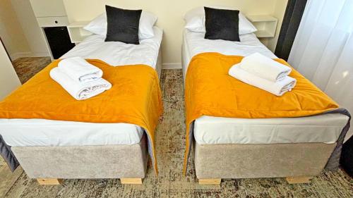 two beds in a room with orange sheets and towels at ApartHotel Centrum - parking free in Białystok