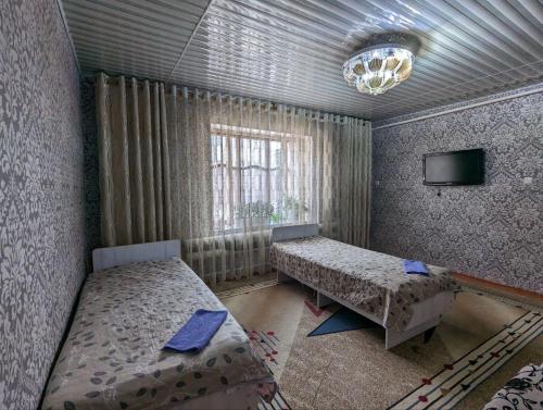 a bedroom with two beds and a tv in it at Olzho Hostel in Karakol