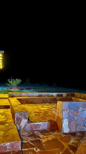 un banco de piedra sentado en una acera por la noche en مزرعة القمة en Mogayra