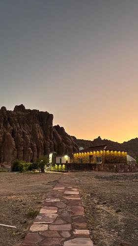 ein Gebäude in der Wüste mit einem Berg im Hintergrund in der Unterkunft مزرعة القمة in Mogayra