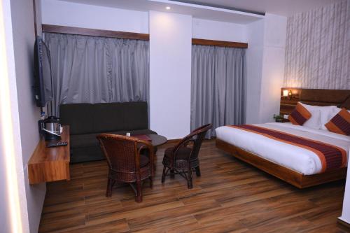 a hotel room with a bed and a table and chairs at Hotel Zion Inn, Cantonment, Varanasi in Varanasi