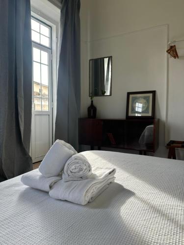 een wit bed met twee vouwhanddoeken erop bij Ti Maria Guest House in Faro