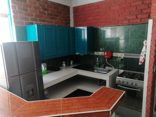 eine Küche mit blauen Schränken und einer roten Backsteinwand in der Unterkunft Alojamiento en cabaña in Fúquene