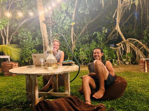 dos personas sentadas alrededor de una mesa con un ordenador portátil en PineApple Surf, en Ahangama