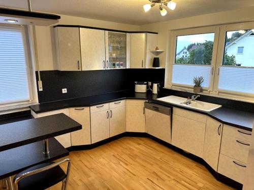 Una cocina con gabinetes blancos y una encimera negra. en Weideblick, traumhaft wohnen im Schwarzwald, en St. Georgen im Schwarzwald