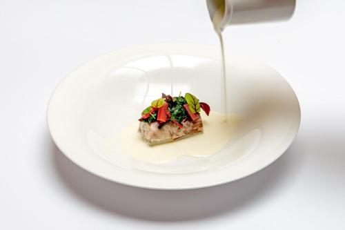 a white plate with a piece of food with a fork at Relais & Spa Castello di Casiglio in Erba