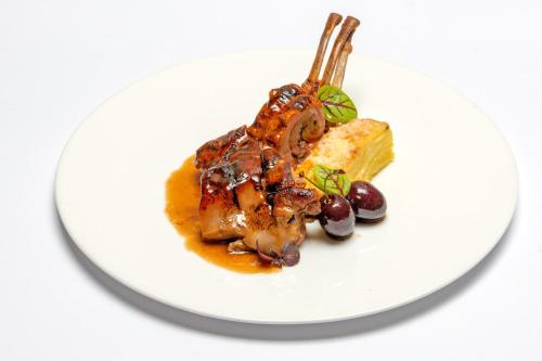 a white plate of food with meat and grapes at Relais & Spa Castello di Casiglio in Erba