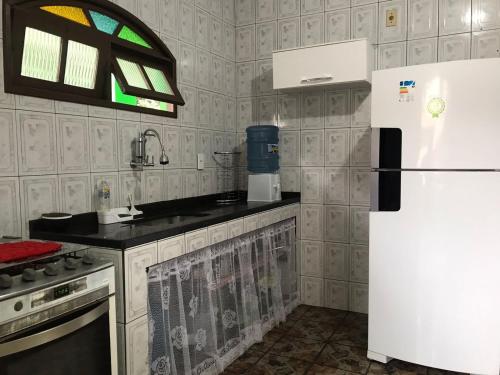 eine Küche mit einem weißen Kühlschrank und einem Fenster in der Unterkunft Casa no centro de Arraial do Cabo in Arraial do Cabo