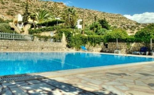 a large blue swimming pool in front of a mountain at Armonia Hotel in Matala