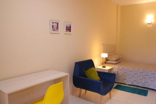Un dormitorio con una silla azul y una cama en De la Mora Hostal, en Fernando de la Mora