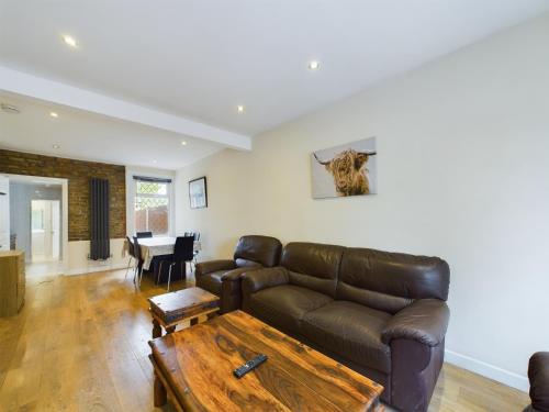 a living room with a leather couch and a table at Cosy 4 bedroom, 3 bathroom home - 5 mins from East Croydon station in South Norwood