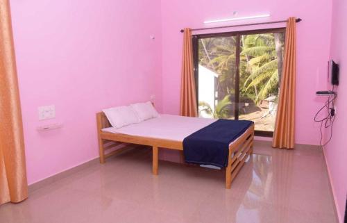 a small bedroom with a bed and a window at Yash Homestay in Malvan