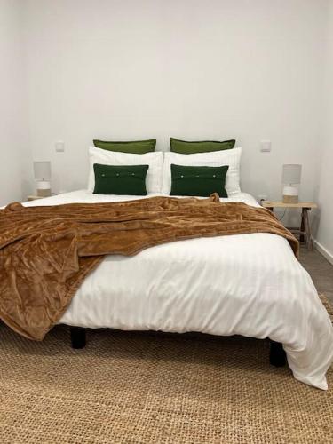 a bedroom with a large bed with green and white pillows at Casa da Xica in Torrão