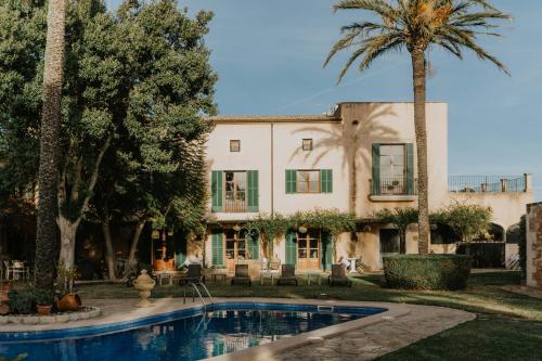 a house with a swimming pool and palm trees at Finca Es Llobets - Adults Only in S'Estanyol de Migjorn