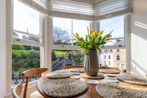 a dining room table with chairs and a vase with flowers at Flat 1, Church House in Ilfracombe