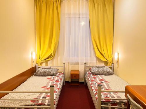 two beds in a room with yellow curtains at Fry House in Warsaw