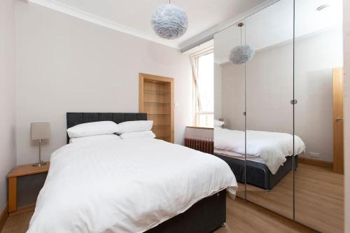 um quarto com uma grande cama branca e um espelho em Newington em Edimburgo