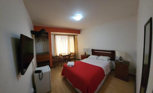 1 dormitorio con 1 cama con manta roja en Hostal El Candelabro, en Pisco