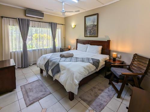 um quarto com uma cama, uma cadeira e uma janela em Room in Villa - Zambezi Family Lodge - Lion Room em Victoria Falls