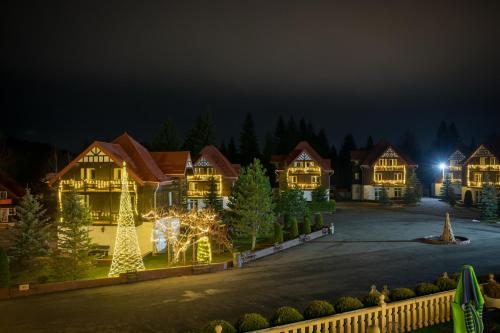 a house decorated with christmas lights and a christmas tree at Monterai Resort in Poiana Brasov