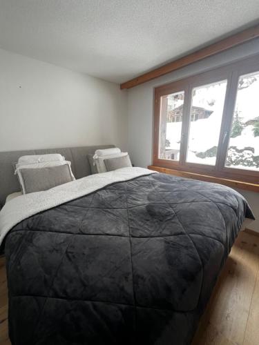 a large bed in a room with a large window at WEF Davos - Klosters Comfort Retreat with Fireplace, Pool & Sauna in Klosters Serneus