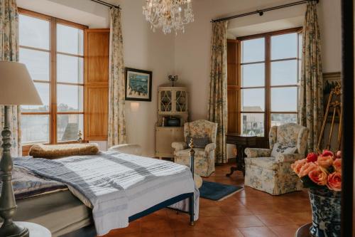 a bedroom with a bed and chairs and windows at Finca Es Llobets - Adults Only in S'Estanyol de Migjorn