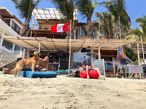 a dog is standing on the beach with people at Wiracocha Hostal Máncora - Surf Camp in Máncora