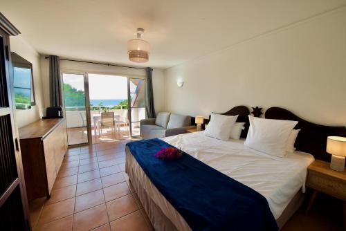 a bedroom with a bed with a blue blanket at Studio OLIA - plages, piscines et vue mer! in Sainte-Anne