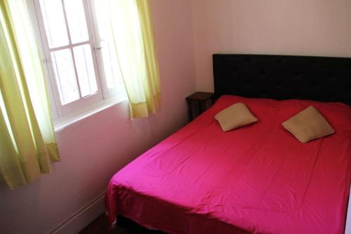 1 dormitorio con cama roja y ventana en Cabaña, hospedaje Vegetariano en San Esteban