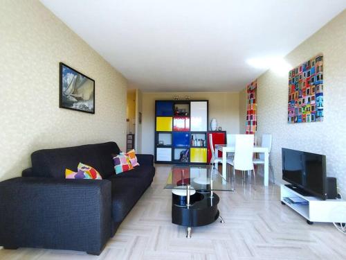 un salon avec un canapé noir et une table dans l'établissement 2 pièces proche golf Mandelieu, à Mandelieu-la-Napoule