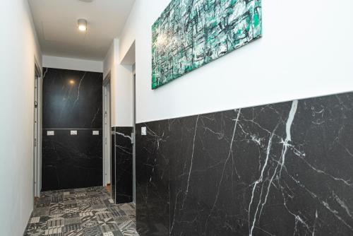 a bathroom with black marble walls and a painting on the wall at Hurban Apartments Venezian in Trieste