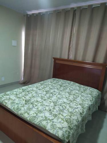 a bedroom with a bed with a wooden frame and curtains at Quitinete para casal in Brasília
