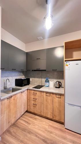 a kitchen with wooden cabinets and a white refrigerator at Lovely Aparthotel in Tsaghkadzor in Tsaghkadzor