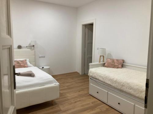 biała sypialnia z 2 łóżkami i lustrem w obiekcie Andy Apartmán Jáchymov w mieście Jáchymov