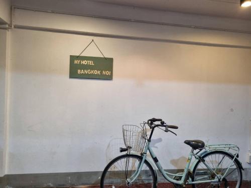 a bike parked next to a wall with a sign at My Hotel Bangkok Noi in Bangkok Noi