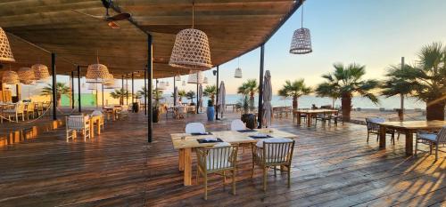 ein Restaurant am Strand mit Tischen und Stühlen in der Unterkunft L'azure Beach Resort in Khuraybah