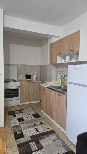 eine Küche mit Holzschränken und einem weißen Kühlschrank in der Unterkunft Apartman stan Konjic in Konjic