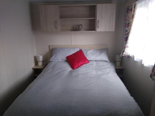 a bed with a red pillow on top of it at CHANNI in Prestatyn