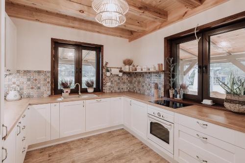 a large kitchen with white cabinets and windows at Stacja Jacnia in Jacnia