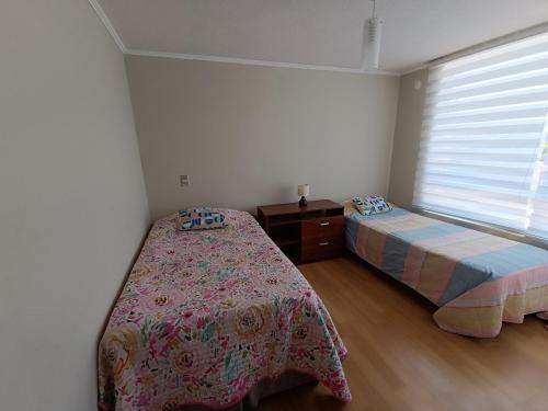 a bedroom with two beds and a window at Departamento La Serena in La Serena