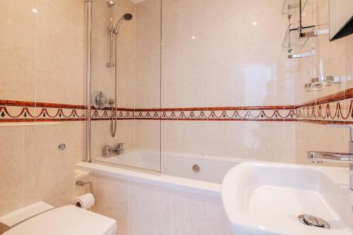 a bathroom with a toilet and a shower and a sink at The Penthouse Westhaven Aberdyfi in Aberdyfi