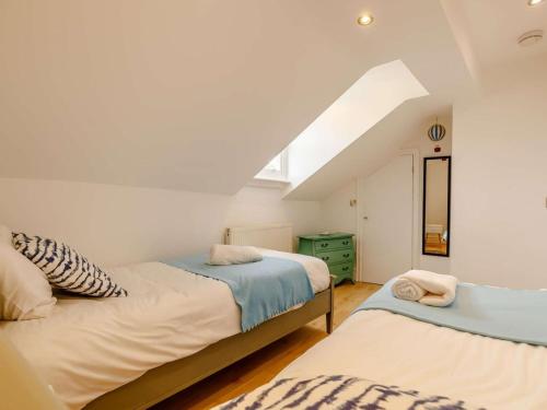 a attic bedroom with two beds and a window at The Penthouse Westhaven Aberdyfi in Aberdyfi