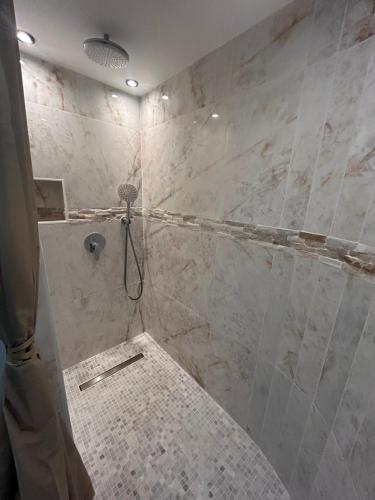 La salle de bains est pourvue d'une douche et de carrelage. dans l'établissement Spa Jacuzzi Moon White, à Vaudherland