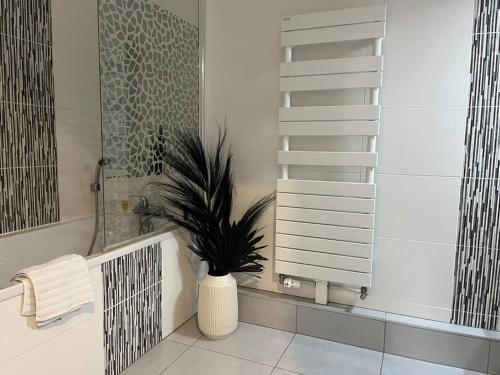 a bathroom with a plant in a white vase at A few steps from BASEL with Balcony and free parking in Saint-Louis
