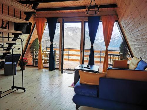 - un salon avec un canapé bleu et de grandes fenêtres dans l'établissement Arsha View, à Kazbegi