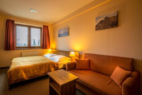 a hotel room with a bed and a couch at Vila Borievka in Vysoke Tatry - Tatranska Lomnica.