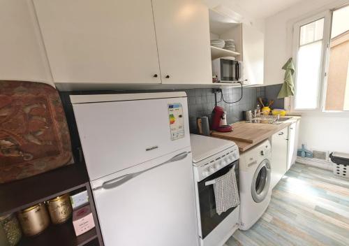 Il comprend une cuisine équipée d'un réfrigérateur blanc et d'une cuisinière. dans l'établissement 1 mois minimum - Appartement Porte Saint Cloud - Parc des Princes, à Boulogne-Billancourt