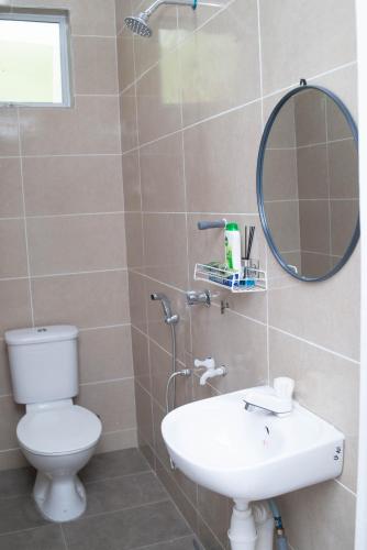 a bathroom with a toilet and a sink and a mirror at Qiu's Event House Std Double Room in Kuala Berang
