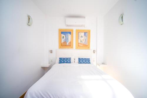 a white bedroom with a large bed with blue pillows at Ático de Lujo Plaza Ayuntamiento in Valencia
